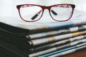 Une pile de journaux et une paire de lunette en guise de décoration